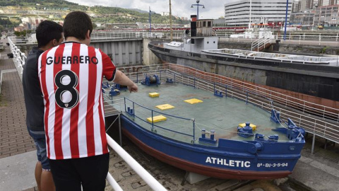 Dos jóvenes observan la legendaria gabarra con la que el Athletic Club celebró sus títulos en 1983 y 1984. EFE/ Miguel Toña Dos jóvenes observan la legendaria gabarra con la que el Athletic Club celebró sus títulos en 1983 y 1984. EFE/ Miguel Toña