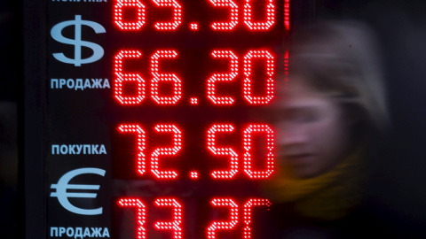 Una mujer pasea en Moscú frente a una pantalla que muestra el cambio de dólar y euros a rublos, la moneda rusa. REUTERS/Maxim Shemetov