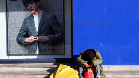 Un sintecho descansa junto al escaparate de una tienda en una calle en Pekín (China). EFE/ Wu Hong Un sintecho descansa junto al escaparate de una tienda en una calle en Pekín (China). EFE/ Wu Hong