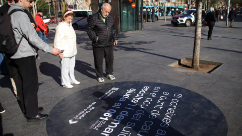 Diverses persones llegeixen el missatge del vinil de plaça Universitat Diverses persones llegeixen el missatge del vinil de plaça Universitat
