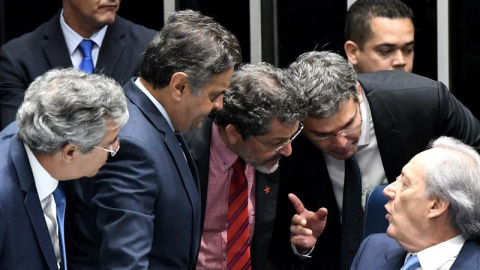 El presidente de la Corte Suprema, Ricardo Lewandowski (d), garante constitucional del proceso, habla con varios senadores durante la lectura del informe en que se recomienda avanzar hacia la destitución de la presidenta suspendida del país