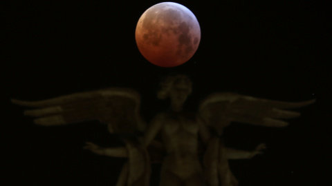 La luna durante el eclipse sobre la Victoria Alada, la estatua que corona el edificio Metrópoli en Madrid, España. REUTERS/Sergio Perez