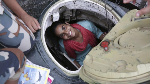 Una joven sonríe desde dentro de un tanque en la exposición "Conoce a tu ejército" en Amritsar (India). La exposición, organizada por el ejército indio, se celebra del 10 al 16 de agosto y tiene el objetivo de animar a los jóvenes a enrolar