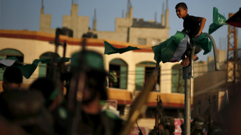 Un niño palestino mira a militantes de Hamas durante un desfile militar que marca el primer aniversario de la matanza de los comandantes militares de Hamas Abu Shammala y al- Attar en Rafah, en el sur de la Franja de Gaza. REUTERS