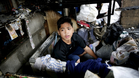 Un niño se recupera ropa escondida en un congelador después de un incendio en un barrio residencial en Paranaque,Filipinas. REUTERS