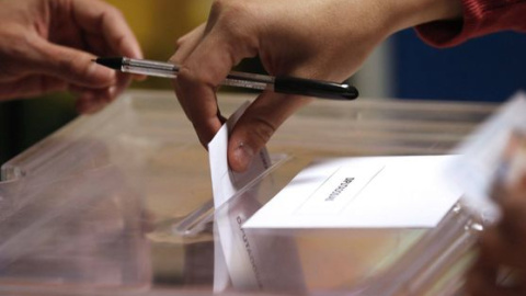 Un votante introduce su papeleta en una urna. Un votante introduce su papeleta en una urna.