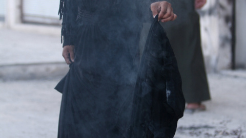 Una mujer quema el niqab tras ser evacuada por las SFD de la ciudad siria de Manbiy, arrebatada al Estados Islámico.- REUTERS/Rodi Said Una mujer quema el niqab tras ser evacuada por las SFD de la ciudad siria de Manbiy, arrebatada al Estados Islámico.- REUTERS/Rodi Said