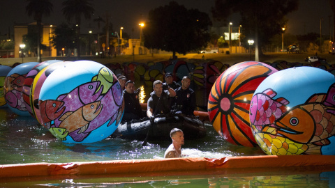 Oficiales de la policía de Los Ángeles y los miembros de la Unidad de Buceo Submarino acercan a una persona a través de la exposición "Esferas de MacArthur Park" en Los Ángeles, California 24 de agosto de 2015. REUTERS / Mario Anzuoni