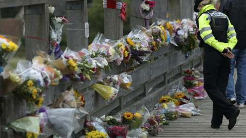 Una oficial de la policía observa las ofrendas que dejan cerca de donde se estrelló un jet de combate Hawker Hunter en una exhibición de acrobacia en la carretera A27 en Shoreham cerca de Brighton, Reino Unido 25 de agosto de 2015. Según fu