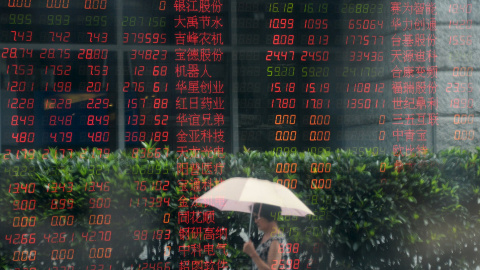 Una mujer pasa junto al ventanal de una firma de broker en Shanghai.  REUTERS/China Daily