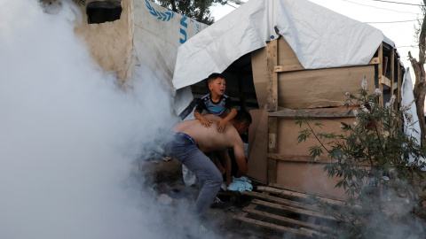 Un migrante coge a un niño mientras huyen de gases lacrimógenos disparados por la policía antidisturbios durante una manifestación, después de un incendio en el campamento de Moria en la isla de Lesbos. REUTERS/Giorgos Moutafis Un migrante coge a un niño mientras huyen de gases lacrimógenos disparados por la policía antidisturbios durante una manifestación, después de un incendio en el campamento de Moria en la isla de Lesbos. REUTERS/Giorgos Moutafis