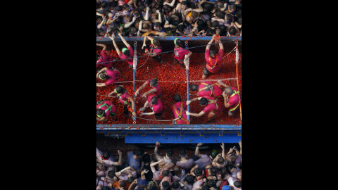 Un camión cargado de tomates pasa por la calle principal de Buñol, abarrotada de gente. EFE