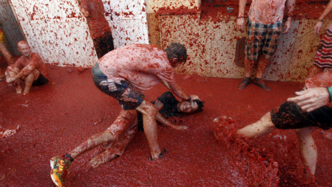 Los participantes en la fiesta de Buñol se divierten en unas calles llenas de los restos de la 'batalla'. EFE