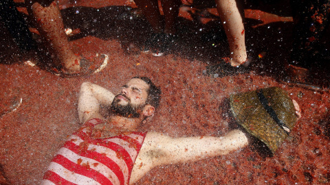 Un manifestante descansa en una calle hasta arriba de tomate. EFE