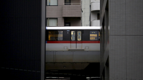Un hombre mira por la ventana del tren entre dos edificios en Tokio, 26 de agosto, 2015. REUTERS/Toru Hanai