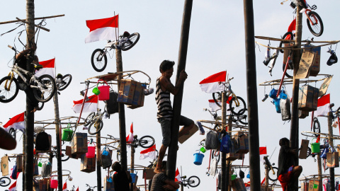 Los participantes escalan postes engrasados ​​para recoger los premios durante un evento de "Panjat Pinang" organizado por la celebración del 71ª aniversario del Día de la Independencia de Indonesia en Jakarta, Indonesia. REUTERS / Iqro Rin