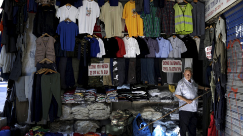 Tendero arregla la ropa fuera de su tienda en el centro de Atenas. REUTERS
