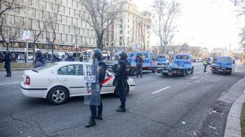 Agentes de la Policía Nacional junto a grúas municipales intentan retener la concentración de taxistas en el Paseo de la Castellana de Madrid. | Ricardo Rubio / Europa Press