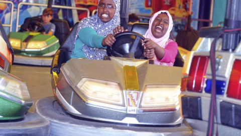 Dos niñas refugiadas se divierten en los coches de choque, en Augsburgo, Alemania. EFE/Stefan Puchner
