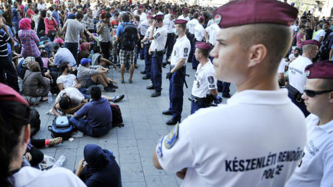 Polícias húngaros observan a los inmigrantes que permanecen ante la estación de ferrocarriles Keleti de Budapest. / EFE Polícias húngaros observan a los inmigrantes que permanecen ante la estación de ferrocarriles Keleti de Budapest. / EFE