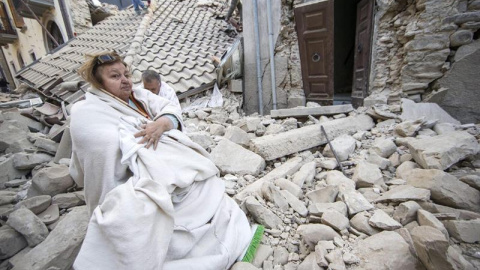 Una mujer permanece sentada sobre los restos de lo que era su casa tras ser derruida a causa del terremoto en Amatrice/EFE
