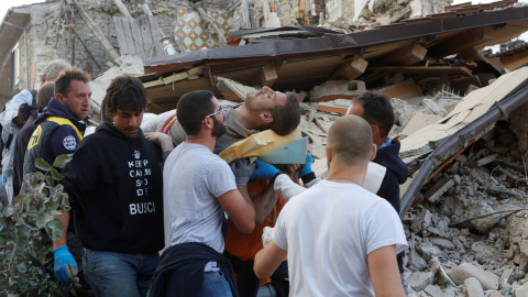 Un hombre, rescatado de entre los escombros, es llevado a hombros por varios voluntarios/REUTERS