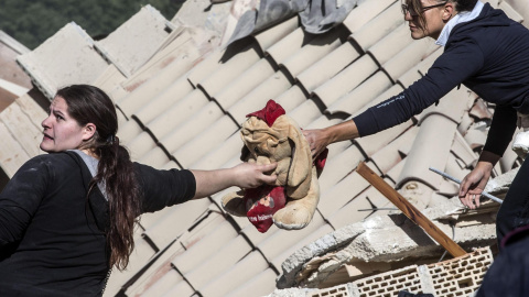 Dos mujeres de los equipos de rescate sostienen un peluche entre los escombros de Amatrice, tras el terremoto en el centro de Italia. EFE/Massimo Percossi