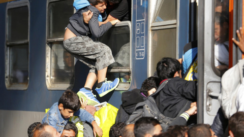 Un hombre, entre la multitud, intenta entrar a un tren por una ventana. /REUTERS