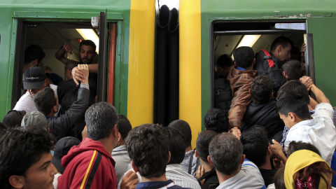 Decenas de refugiados intentan subirse a un vagón de tren entre empujones. /REUTERS