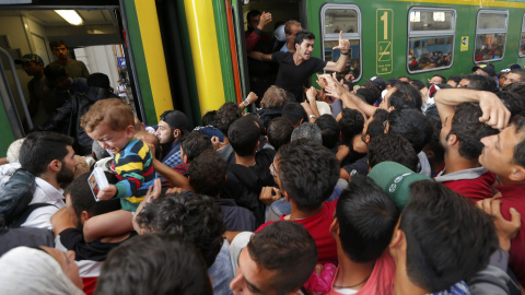 Decenas de refugiados intentan subirse a un vagón de tren entre empujones tras la autorización del Gobierno húngaro. /REUTERS