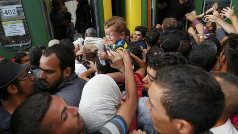 Decenas de refugiados intentan subirse a un vagón de tren entre empujones. /REUTERS