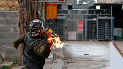 Un palestino lanza un cóctel molotov contra soldados israelíes durante enfrentamientos en Hebrón, Palestina, durante las protestas con motivo del Día de la Tierra. Los palestinos recuerdan la muerte de seis árabes israelíes en Galilea, en e