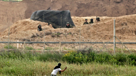 Un palestino arroja piedras a los soldados israelíes al otro lado de la frontera durante los enfrentamientos después de las manifestaciones del Día de la Tierra al este de la ciudad de Gaza.- MAHMUD HAMS / AFP