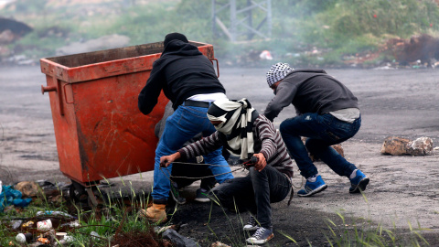 Varios palestinos lanzan piedras durante los enfrentamientos con soldados israelíes en la ciudad cisjordana de Ramala.-  EFE/Alaa Badarneh