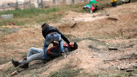Un palestino ayuda a un compañero herido durante los enfrentamientos con soldados israelíes en el este de Beit Hanun, norte de la Franja de Gaza.-  EFE/Mohammed Saber