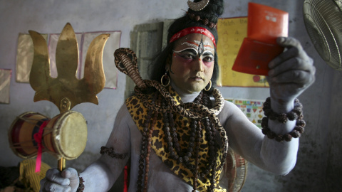 Un hombre vestido como un Shiva se mira en el espejo mientras se prepara para participar en una procesión religiosa en la víspera del festival de Janmashtami en Amritsar, India, 4 de septiembre de 2015. REUTERS / Munish Sharma