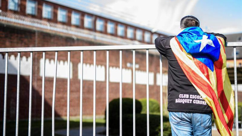 Un hombre con una estelada atada al cuello observa el interior de la prisión de Neumünster, donde está Puigdemont. | CLEMENS BILAN (EFE) Un hombre con una estelada atada al cuello observa el interior de la prisión de Neumünster, donde está Puigdemont. | CLEMENS BILAN (EFE)