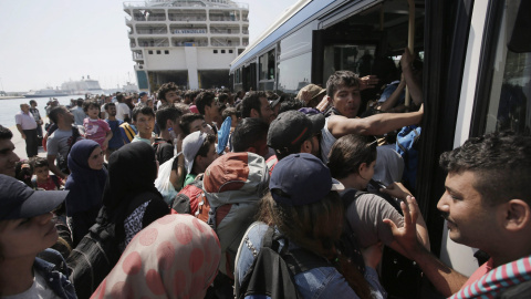 Refugiedos, en su mayoría sirios, tratan de entrar en un autobús tras desembarcar del ferry  'Eleftherios Venizelos' en el puerto ateniense del Pireo.. EFE/EPA/YANNIS KOLESIDIS
