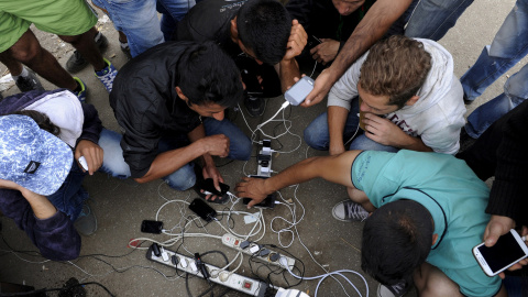 Cargan sus teléfonos móviles mientras esperan para cruzar la frontera de Grecia con Macedonia, cerca del pueblo de Idomeni, 6 de septiembre de 2015. REUTERS / Alexandros Avramidis