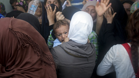 Un bebé llora durante enfrentamientos entre los refugiados afganos y sirios por la prioridad que se está dando a estos últimos en el proceso de registro en el puerto de Mitilene, en la isla griega de Lesbos, 6 de septiembre de 2015. REUTERS