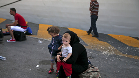 Una refugiada siria sostiene a su hijo mientas espera a subirse a un autobús después de su llegada a bordo del buque de pasajeros Tera Jet en el puerto de El Pireo, cerca de Atenas, Grecia 6 de septiembre de 2015. REUTERS / Alkis Konstantin