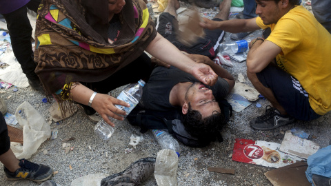 Ayudan a un hombre después de desmayarse por el calor tras los enfrentamientos en el proceso de registro en el puerto de Mitilene, en la isla griega de Lesbos, 5 de septiembre de 2015. REUTERS / Dimitris Michalakis