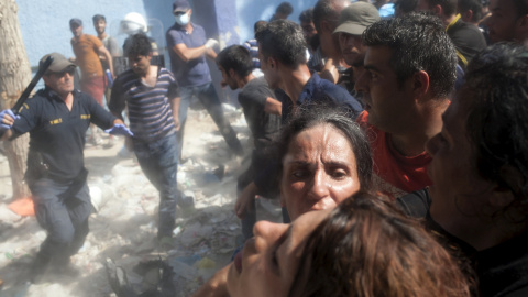 Un policía corre con una porra para hacer retroceder a los refugiados y los inmigrantes en la espera del proceso de registro en el puerto de Mitilene, en la isla griega de Lesbos, 5 de septiembre de 2015. REUTERS / Dimitris Michalakis