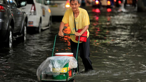 Un ciudadano filipino empuja un carro por una carretera inundada que lleva al aeropuerto en Parañaque, Filipinas. EFE/Eugenio Loreto