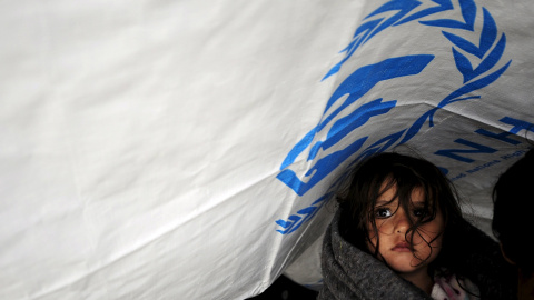 Una niña espera con otros migrantes bajo la lluvia en un campo de refugiados cerca de Gevgelija , Macedonia, después de entrar en el país por la frontera con Grecia. REUTERS