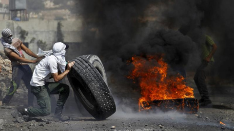 Palestinos lanzan queman neumáticos durante una protesta contra los asentamientos judíos en Wadomem cerca de Nablus (Palestina). Nueve palestinos han resultado heridos durante los enfrentamientos con los soldados durante la manifestación. E
