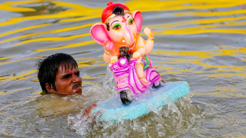 Un hombre se sumerge junto a un ídolo del dios hindú Ganesh, el dios de la prosperidad, en un estanque en el segundo día del festival de Ganesh Chaturthi en Ahmedabad, India. REUTERS / Dave Amit