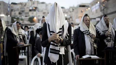Judíos ortodoxos se cubren la cabeza con mantos de oración mientras rezan toda la noche por el perdón, o Selijot, en el Muro de las Lamentaciones. EFE / ABIR SULTAN