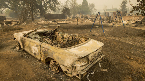 Un coche y unos columpios, tras el paso del fuego por Middletown, en California. REUTERS