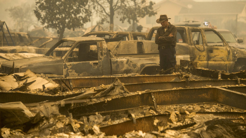 Un hombre graba imágenes de las casas y vehículos quemados tras el paso del incendio. REUTERS
